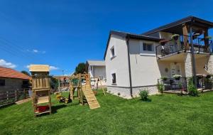 a yard with a playground in front of a house at Velebitska Vila in Gračac
