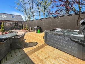 a hot tub on a wooden deck with a fence at West Mains Barn - Uk51957 in Kilbirnie