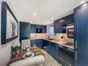 a kitchen with blue cabinets and a wooden table at West Mains Barn - Uk51957 in Kilbirnie +4 photos
