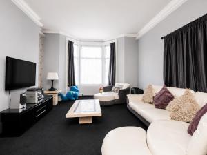 a living room with white furniture and a flat screen tv at Highfield Hotel Blackpool in Blackpool