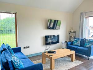 a living room with two blue couches and a coffee table at Jasmine Lodge in Garton