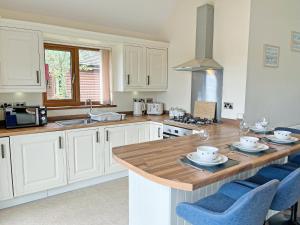 a kitchen with white cabinets and a wooden counter top at Jasmine Lodge in Garton