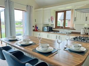 a kitchen with a wooden table with plates and wine glasses at Jasmine Lodge in Garton +7 photos