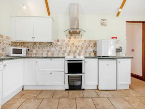 a kitchen with white cabinets and white appliances at Hayloft - Uk49909 in Blandford Forum