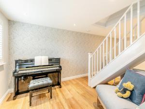 a piano in a living room with a staircase at Anne's Cottage in Strines