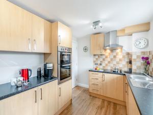 a kitchen with wooden cabinets and black counter tops at Anne's Cottage in Strines