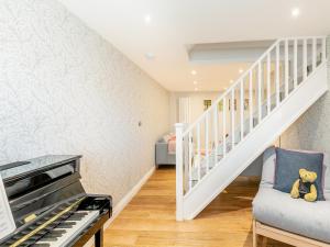 a living room with a piano and a staircase at Anne's Cottage in Strines