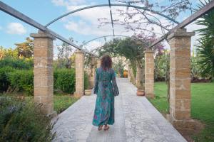 a woman in a green dress walking down a walkway at Masseria L'Uliveto Agri Resort in Otranto +68 photos