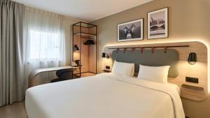 a hotel room with a large bed and a desk at Campanile PRIME - Paris - Porte de Bagnolet in Bagnolet