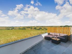 a patio with a couch and a view of a field at The Old Coach Garage in Gerrans