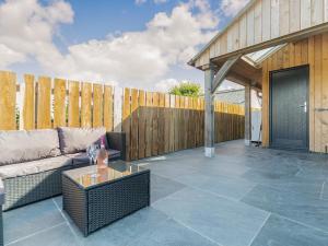 a patio with a couch and a wooden fence at The Old Coach Garage in Gerrans