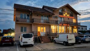 a building with two white vans parked in front of it at Pensiunea Rozeclas in Sînmartin +64 photos