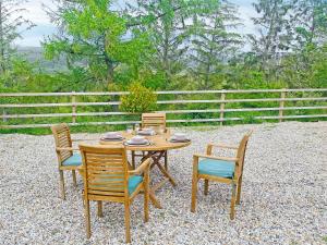 a wooden table and chairs sitting on a gravel patio at Night Sky Cottage in Kielder