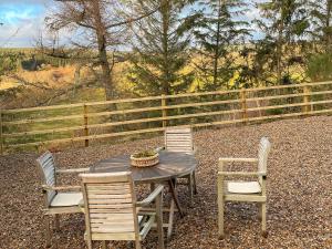 a table and four chairs with a table and a fence at Night Sky Cottage in Kielder