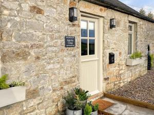 a stone building with a door and potted plants at Night Sky Cottage in Kielder