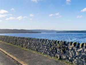 a stone wall next to a large body of water at Night Sky Cottage in Kielder +17 photos
