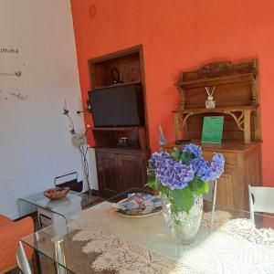 a living room with a table with a vase of blue flowers at Cà dl'Ernesto in Varallo