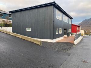 a black house with a wooden deck next to a street at Rogvi's new appartment in Klaksvík +2 photos