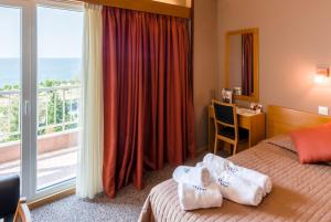 a hotel room with towels on a bed with a balcony at Queen Olga Hotel in Thessaloniki