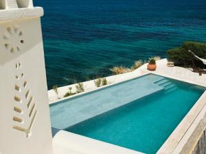a swimming pool with the ocean in the background at Belvedere Mykonos - Main Hotel - The Leading Hotels of the World in Mikonos