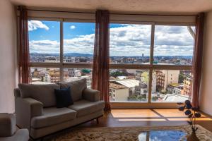 a living room with a couch in front of a large window at Hotel Le Pousse Pousse in Antananarivo