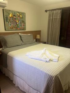 a bedroom with a bed with two towels on it at Praia do Forte - ap Bali Bahia 107 in Praia do Forte +58 photos