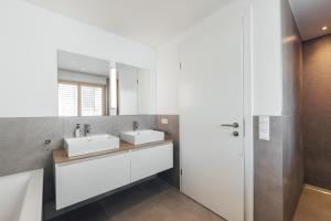 a bathroom with two sinks and a mirror at Bodensee Bergblick Nest by Stadtlandnest in Lochau +30 photos