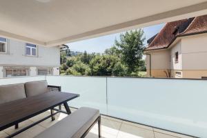 a view from the balcony of a house with a wooden table at Bodensee Bergblick Nest by Stadtlandnest in Lochau