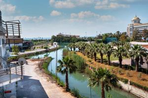a river with palm trees in a city at Riversea Suite & Hotel in Lara