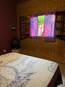 a bed in a bedroom with a window at Tahoma Chalé Rustico Lila Prumirim in Ubatuba