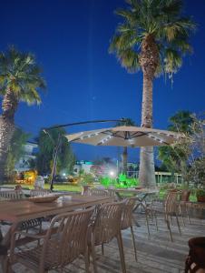 a group of tables and chairs with palm trees at Villa Christina Sea Side A in Hanioti
