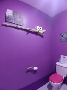a bathroom with a purple wall with a toilet and a shelf at The Laughing Mermaid in Coffee Bay