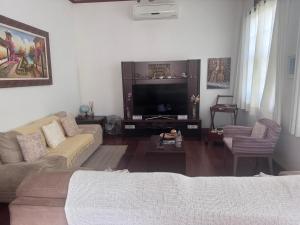a living room with a couch and a tv at Pousada Luar da Serra in Valença
