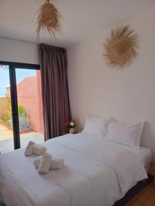 a bedroom with a white bed with towels on it at APPARTEMENT surf camp pour les familles in Oualidia