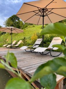 a group of chairs and umbrellas on a wooden deck at A-frame-hub з форелевою риболовлею in Slavske