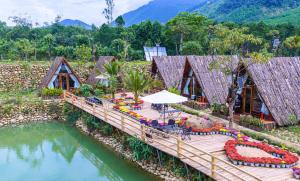 a wooden bridge over a river with a table and chairs at Leaf Village & Farm Làng Lá in Danang