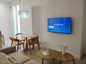 a living room with a couch and a tv on a wall at Apartamento La Font in Pego