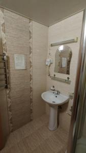 a bathroom with a sink and a shower with a mirror at Comfort Continent in Oktyabrʼ +6 photos