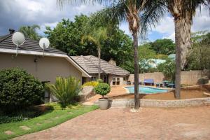 a house with a swimming pool and palm trees at Cashan BnB in Rustenburg