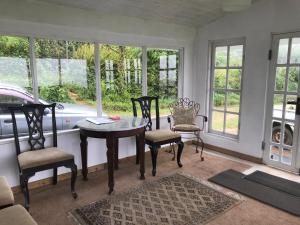 a dining room with a table and chairs and windows at Fair Field Bungalow in Nuwara Eliya