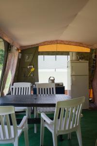 a table and chairs in a kitchen with a refrigerator at Hotel & Glamping Gerhardhof by ALPAMI in Wildermieming