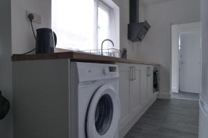 a white washing machine in a room with a window at Modern 3BDR Home l Sleeps 5 l Free Parking l Close to Train station and Shops in Worksop