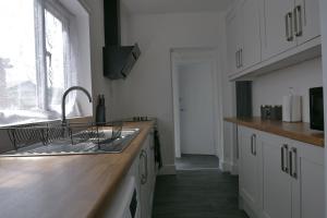 a kitchen with white cabinets and a sink and a window at Modern 3BDR Home l Sleeps 5 l Free Parking l Close to Train station and Shops in Worksop