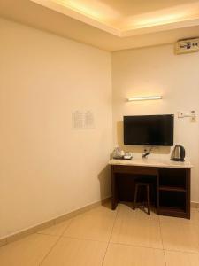 a room with a desk with a television on a wall at New century inn in Bintulu +27 photos