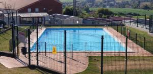 a swimming pool behind a fence with a volleyball net at Altamira Camping in Queveda
