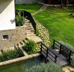 two benches sitting on a stone path next to a pond at Villa Eloris in Pismenovo +7 photos