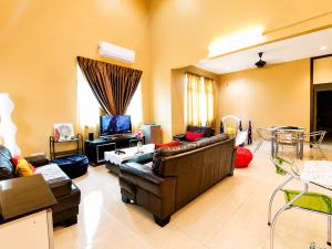 a living room with a couch and a tv at Family Retreat w Kid Pool, BBQ Games Sleeps 10pax Melaka in Kampong Beringin