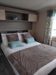 a large bed with two pillows in a bedroom at Thrillseeker - Chalet style caravan next to Fantasy Island, Ingoldmells, 2 dogs max - East Coast Holidays in Skegness