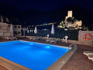 a swimming pool with chairs and umbrellas at night at Alojamientos Peña del Rey in Cazorla