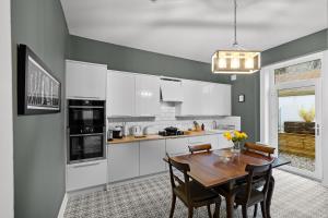 a kitchen with white cabinets and a wooden table at Hermitage Suite - Stylish Shared Accommodation in Dundee